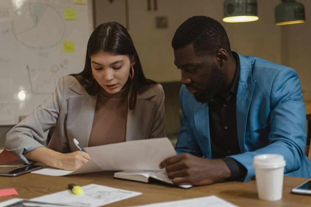 Two colleagues collaborating over documents at an office desk.